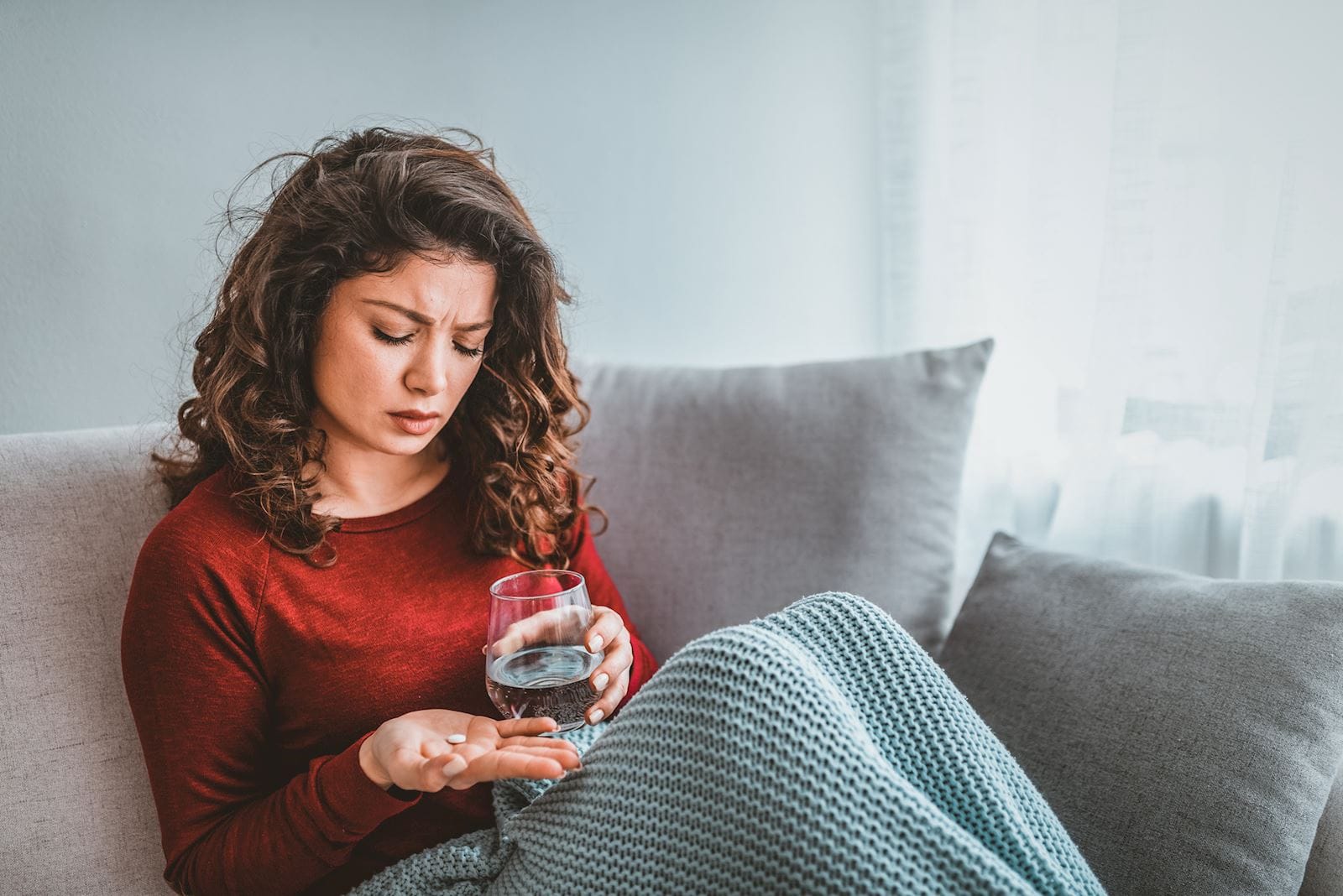 Woman holds pill and glass of water in her hand