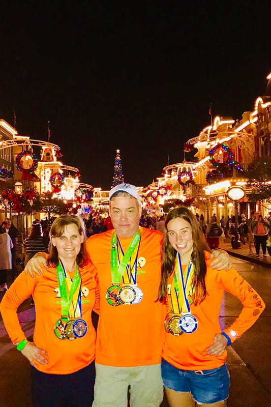 Photo of Lynn and Greg Gaumer, with their daughter wearing medals