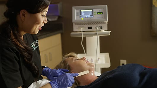 Aesthetician treating woman's neck