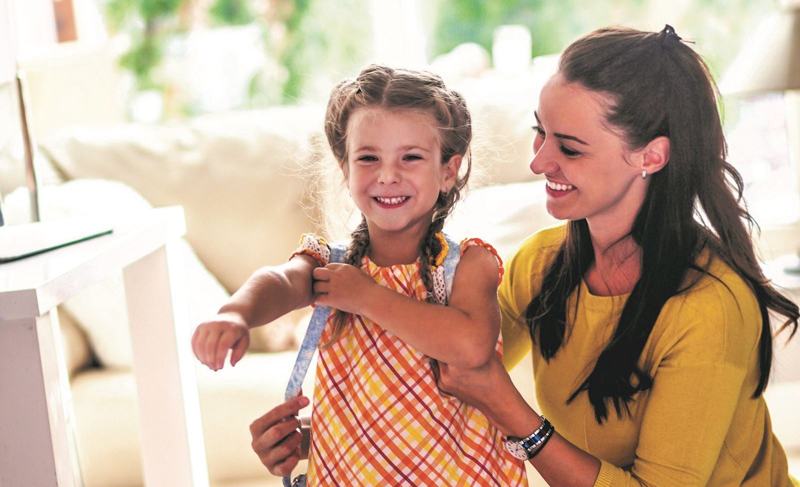 Woman prepares young daughter for school