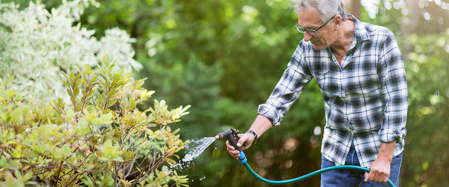 Man spraying hose in garden