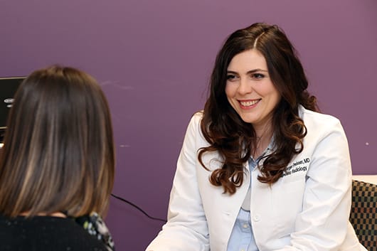 Dr. Preisser sitting, smiling at a patient